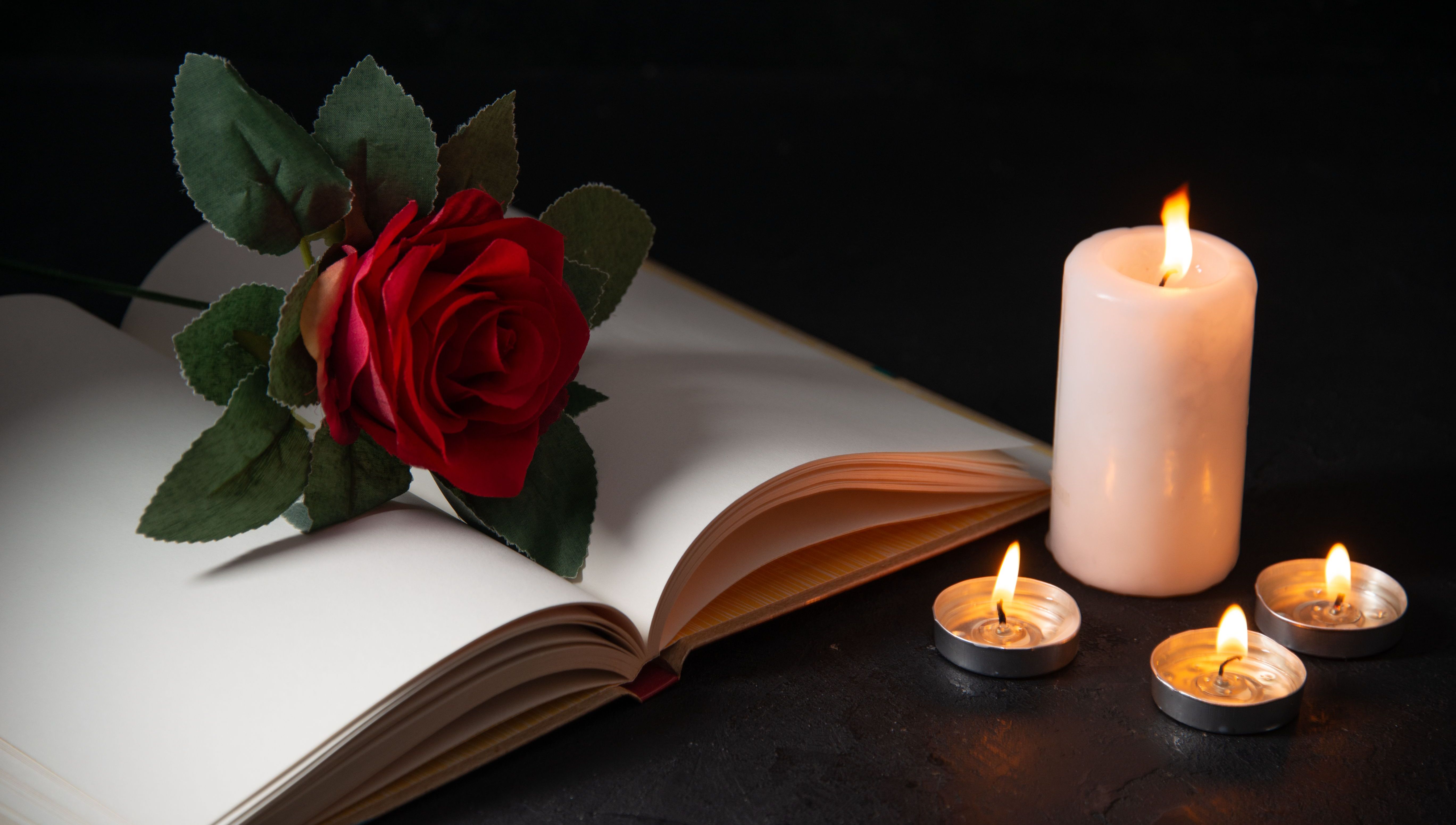 open Bible with a rose on top, 1 lit pillar candle and 3 lit tealights
